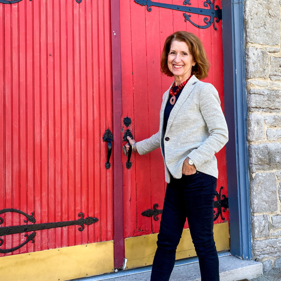 Julie Hullett, owner of Julie Hullett Concierge, LLC, in front of a big red door.