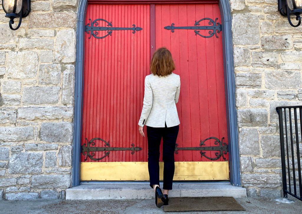 Julie Hullett walking toward a large red door.